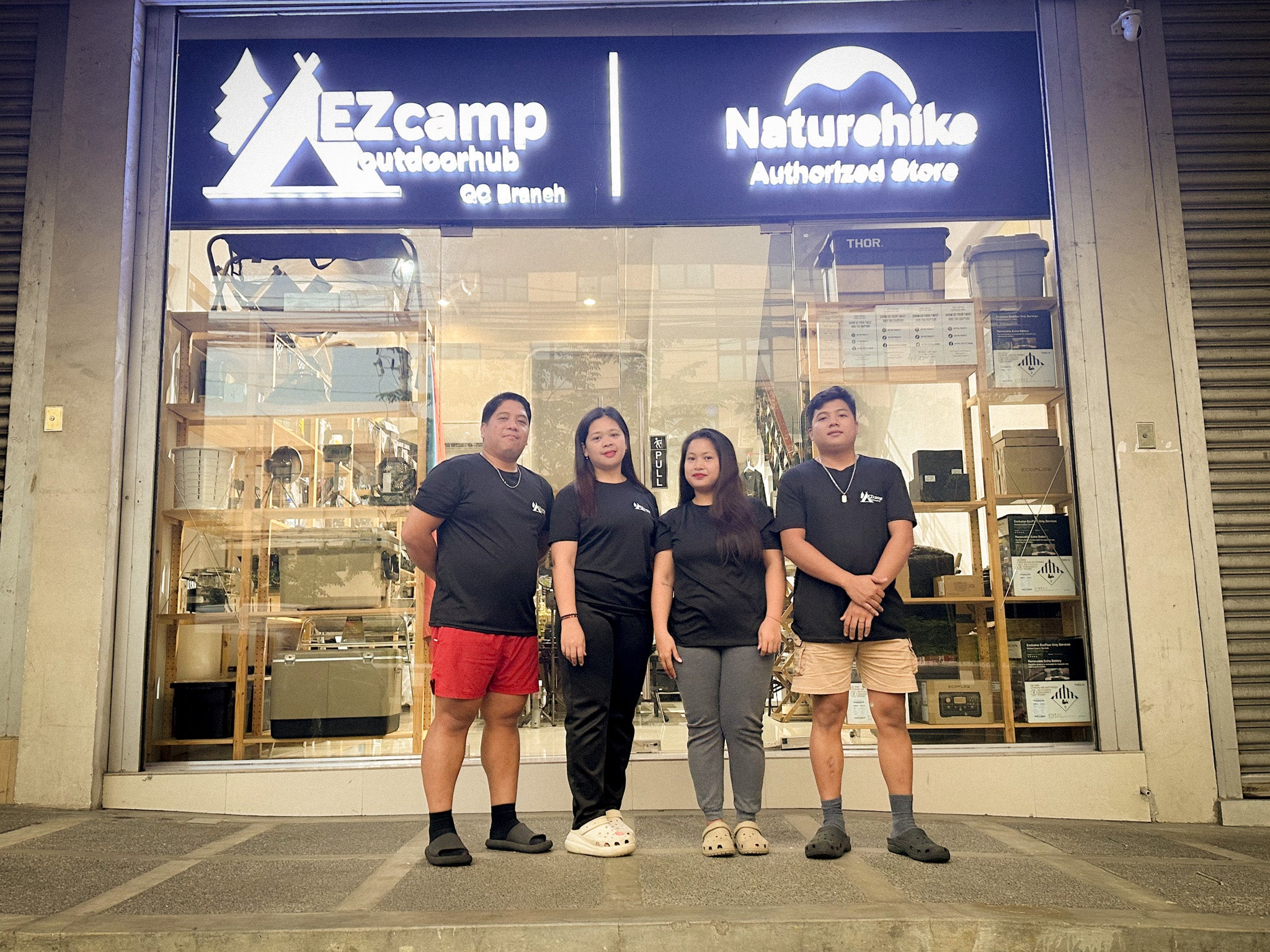 Four people standing in front of a store with EZcamp and Naturehike logos.